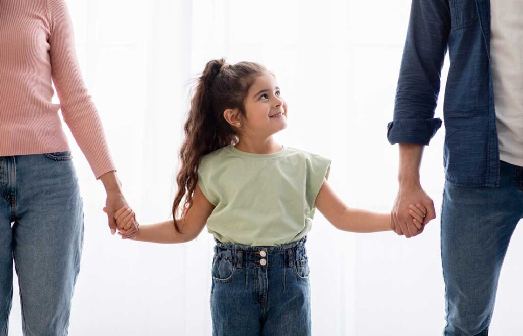 Adoption with a child holding hands of new parents
